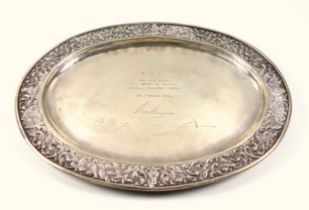 Thai white metal oval presentation dish, the rim embossed with scrolling decoration and 4 Buddhist