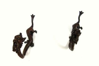 Pair of bronze hooks, each in the form of a creature with a dragon's body and grotesque male head,