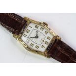 Art Deco 18ct enamel bezel watch, Tonneau shape engraved dial, with gilt Arabic numerals. Engraved