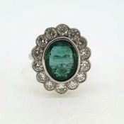 WGA white gold bezel set oval emerald and diamond cluster ring. The emerald is 3.50 carats, with