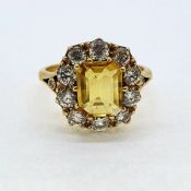A step cut Yellow sapphire sits at the centre of this cluster ring surrounded by 10 round