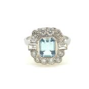 Platinum step cut aqua and diamond cluster ring with baguette diamonds adjacent to the shoulder of t