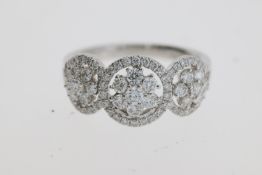 A pretty flower cluster diamond ring, 3 flowers each set inside a halo of diamonds. Estimated to