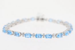 18ct white gold blue topaz and diamond line bracelet. Oval cut blue topaz stones with round