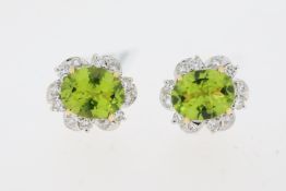 Oval cut peridot and round brilliant diamond halo earrings. Total peridot carat weight approximately