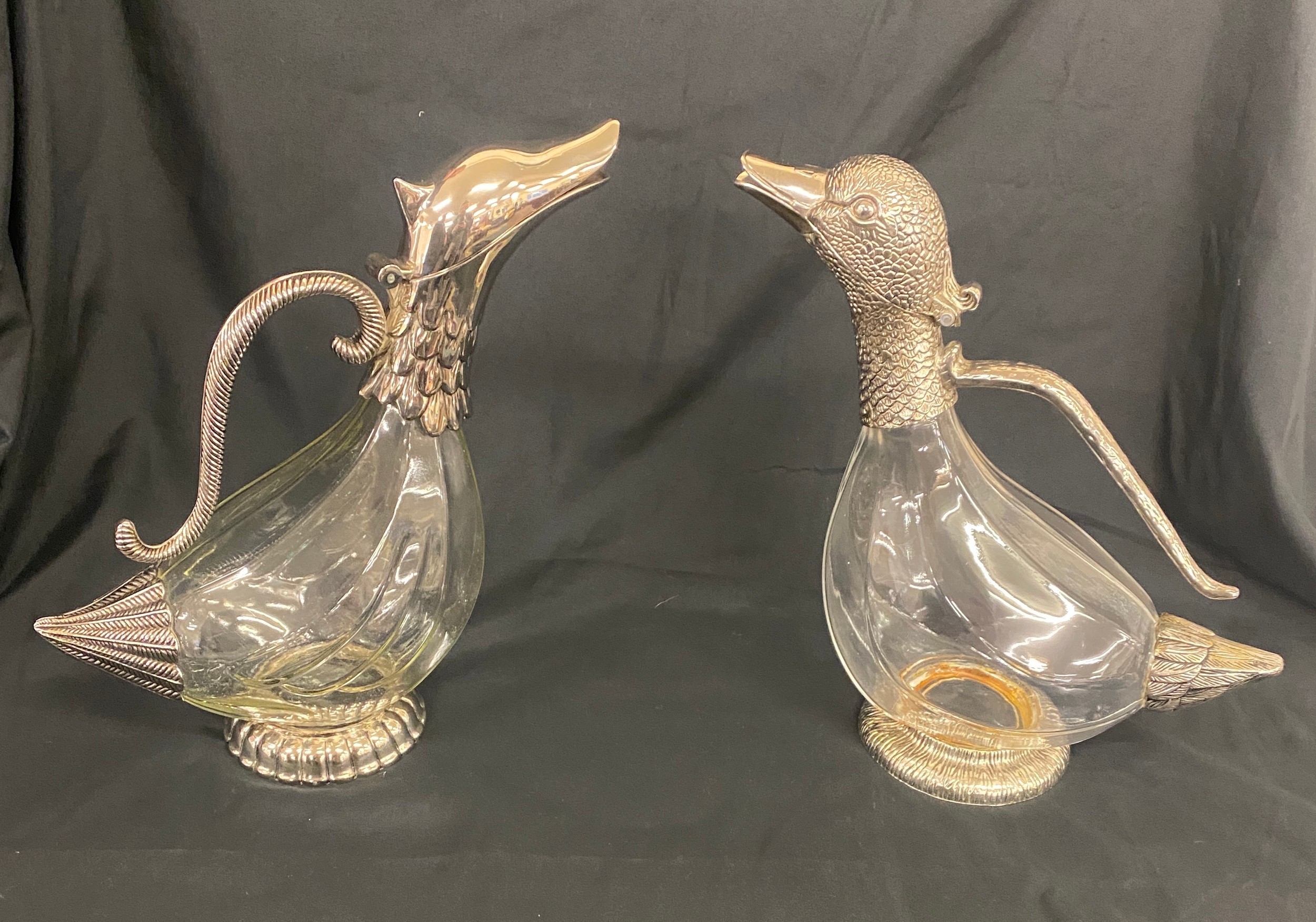 A near pair of glass duck wine decanters with white metal handles and heads