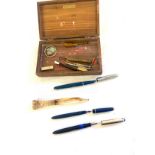 Box containing fountain pens , white metal pencils and a treen bottle pencil