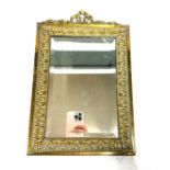 Ornate brass surround bevel edge mirror, brass ribbon design to top measures approximately