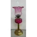 Antique brass collum base cranberry glass oil lamp complete with shade and funnel.