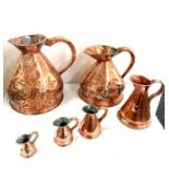 Selection of vintage copper graduating jugs largest measures 14 inches tall