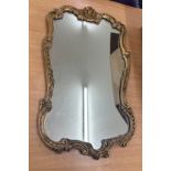 Ornate gilt framed wall mirror measures approx 25 inches long by 14.5 inches wide