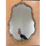 Ornate gilt framed wall mirror measures approx 30 inches tall by 18 inches wide