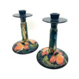 A pair of Moorcroft pottery candlesticks in the Ryden Fields pattern, each having a circular top