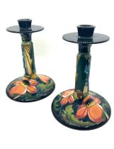 A pair of Moorcroft pottery candlesticks in the Ryden Fields pattern, each having a circular top