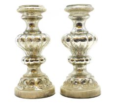 A pair of silvered glass candle stands,