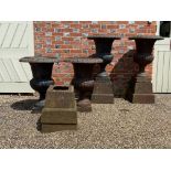 A set of four cast iron campana shaped black painted urns on pedestals