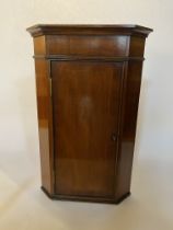 A small George III style mahogany and crossbanded hanging corner cupboard
