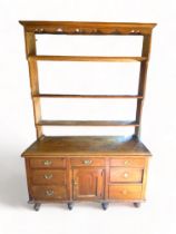 A 19th century pine dresser The upper part with undulating cornice above three shelves, the lower