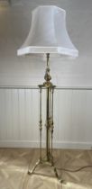 A brass standard lamp On turned support on a tripartite base with scroll feet, together with a cream