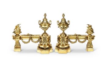 A pair of French gilt bronze chenets In the Louis XVI style, with twin handled and flaming urns and