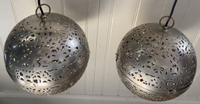 A pair of Moorish style pierced metal hinged globe pendant lights Each 25cm diameter, fitted for
