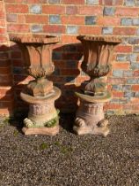 A pair of vintage terracotta Gothic style urns on associated capital pedestals