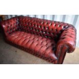 A two seater red leather Chesterfield settee with button back and seat.