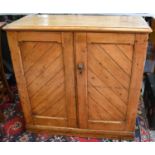 An antique pine kitchen cupboard, the two diagonally panelled doors enclosing two interior shelves