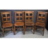 A set of four antique elm and possibly yew wood church chairs with cruciform backs and slab seats.