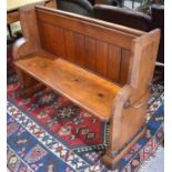 An antique stained pine church pew of small proportions with twin brass handles and cast iron