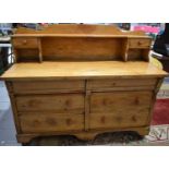 An antique pine dresser of small proportions, the raised back having a single shelf above two