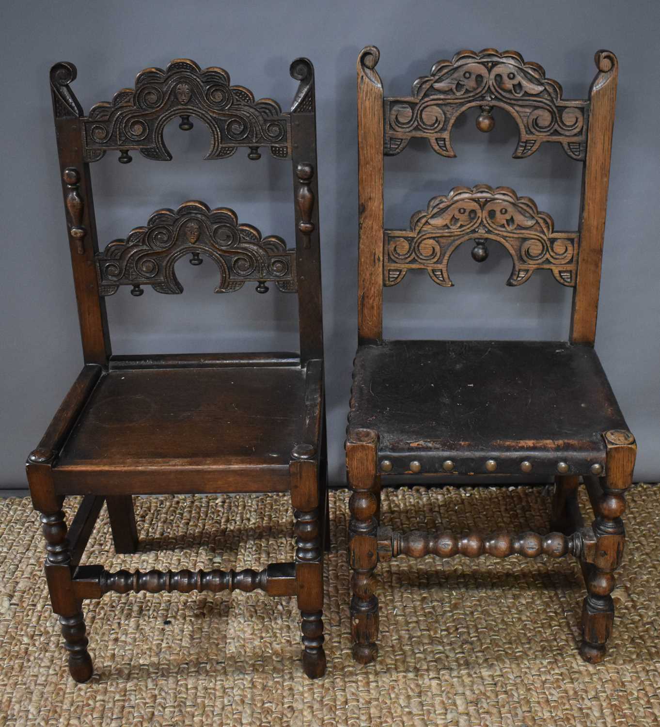 Two 17th century style oak hall chairs with twin arch back rails, carved with decoration, one with