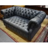 A blue leather Chesterfield settee of small proportions wit button back and seat, raised on turned