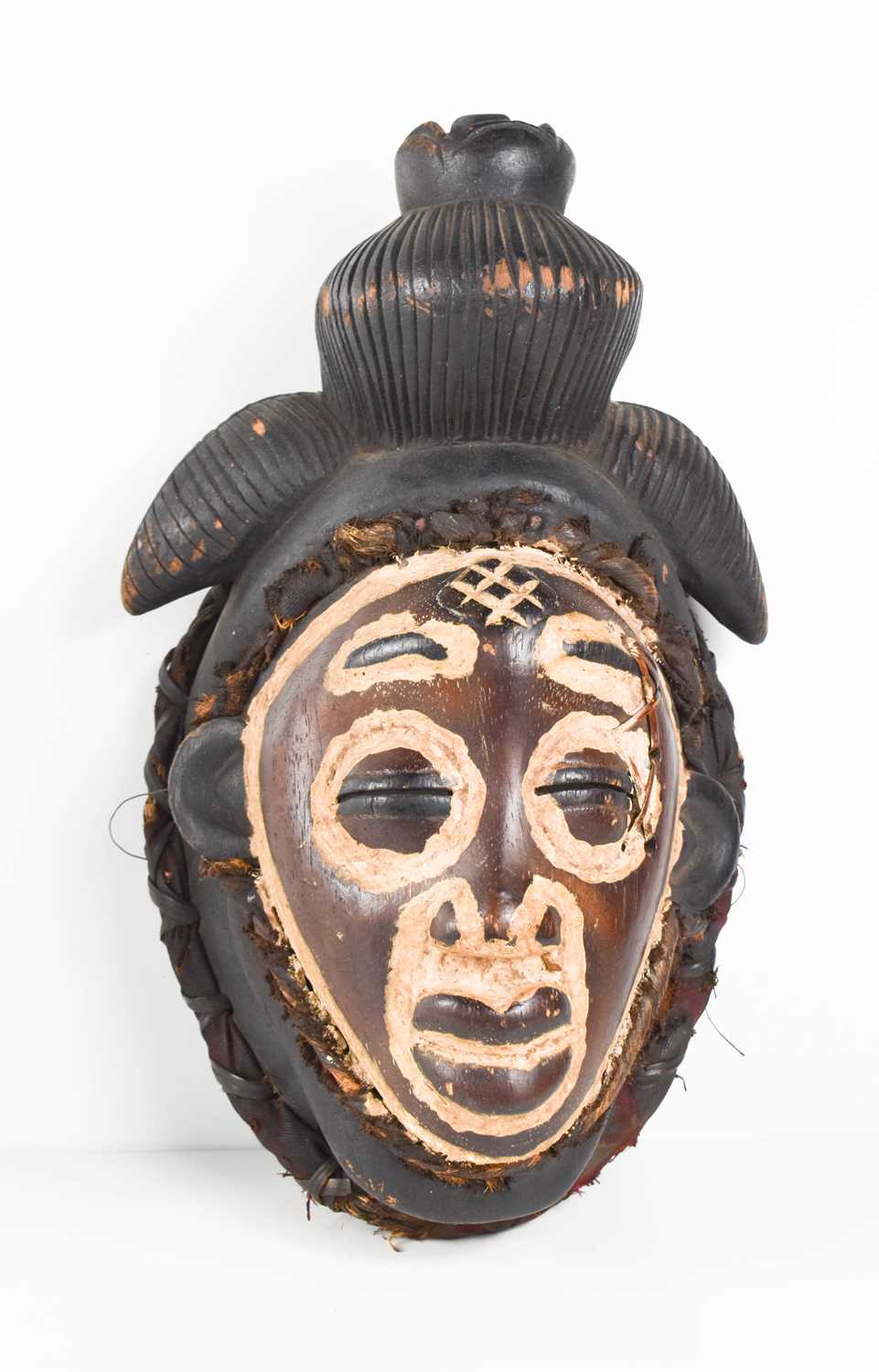 A West African face mask, likely late 19th century Punu, of feminine form, with full lips, coffee