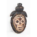 A West African face mask, likely late 19th century Punu, of feminine form, with full lips, coffee