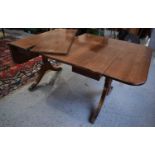 A reproduction mahogany drop leaf dining table with two extra leaves, raised on reeded swept legs,