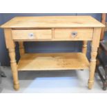 An antique pine side table with two drawers bearing glass knobs above a lower shelf, 71cm high by
