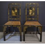 A pair of 19th/20th century Chinese black laquered hall chairs, with caned seats, decorated with