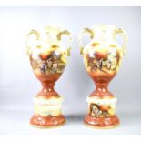 A pair of Pastoral Ware ceramic vases on pedestal bases, depicting rural village scenes with