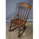 A Victorian elm rocking chair of small proportions with spindle back and bowed arm rails.