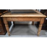 An antique pine kitchen table raised on turned legs, planked top, 76cm by 121cm by 95cm.