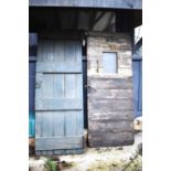 Two large antique oak doors, one with a small window and half painted.