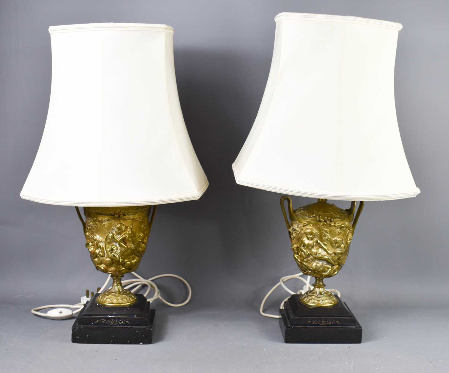 A pair of 19th century gilt metal table lamps, of urn form, modelled in relief to depict classical