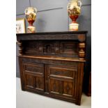 A 17th century oak court cupboard, with cup and cover carved supports fronting two cupboard doors,