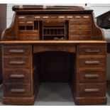 A 1940s oak roll top desk, the interior fitted with drawers and compartments above two banks of four