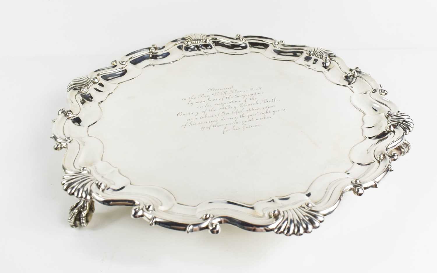 A solid silver salver, Sheffield 1916, with scroll and shell decorated raised border, with three