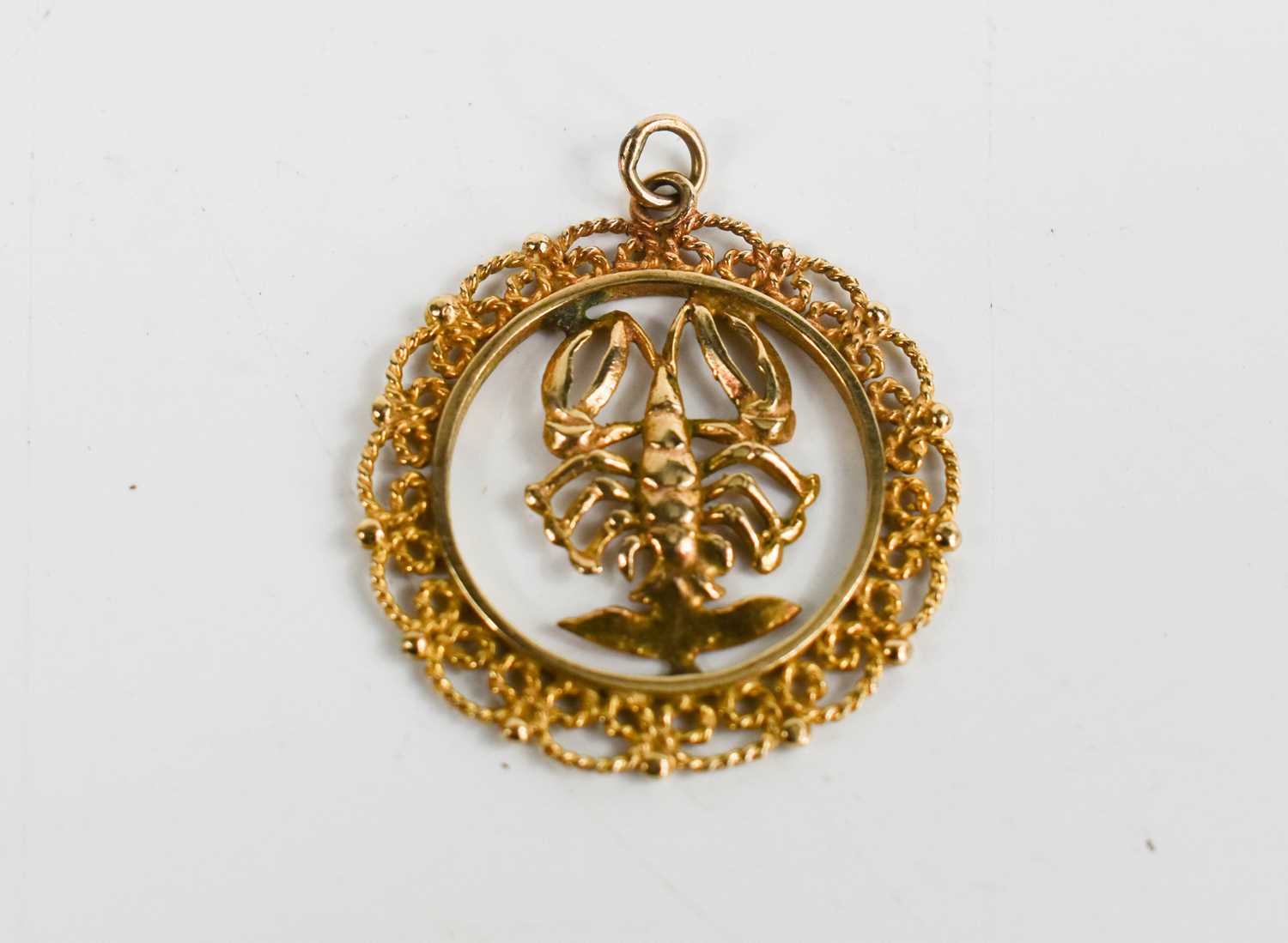 A 9ct gold pendant set with a lobster with filigree border, 3.33g.