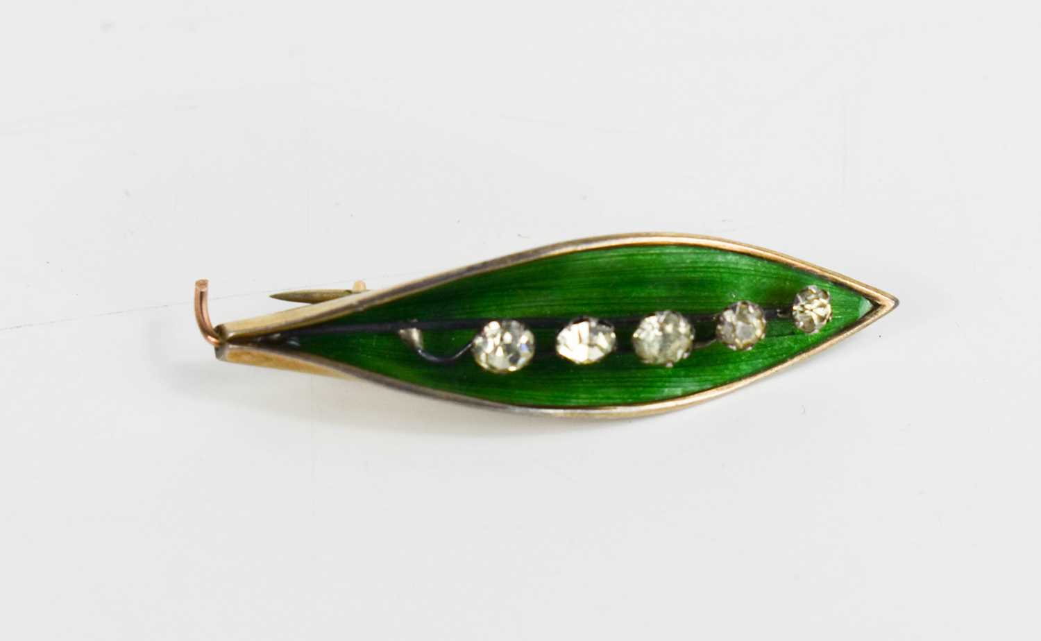 An Art Nouveau enamel and gold lily of the valley brooch, with green enamel leaf surrounding a spray