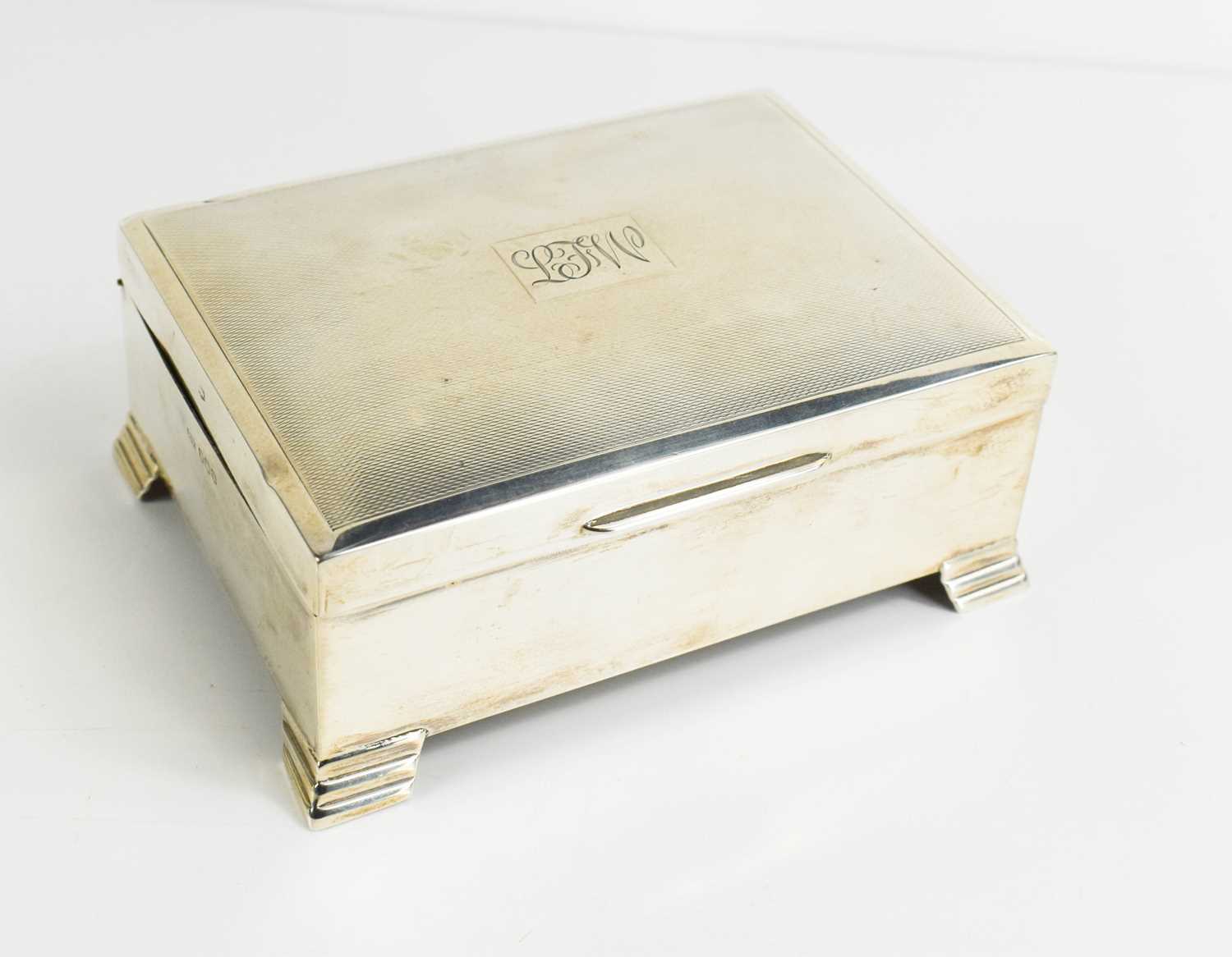 A silver cigarette box with engine turned decoration to the lid, monogram engraved, 11.4 by 8.7 by