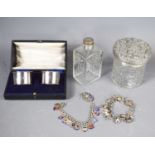 A pair of silver napkin rings in presentation case, glass and silver topped jars, and two silver